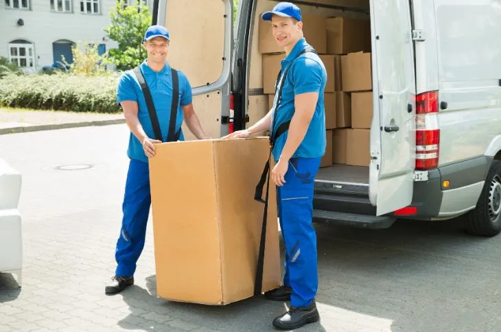 Movers wrapping furniture with protective padding.